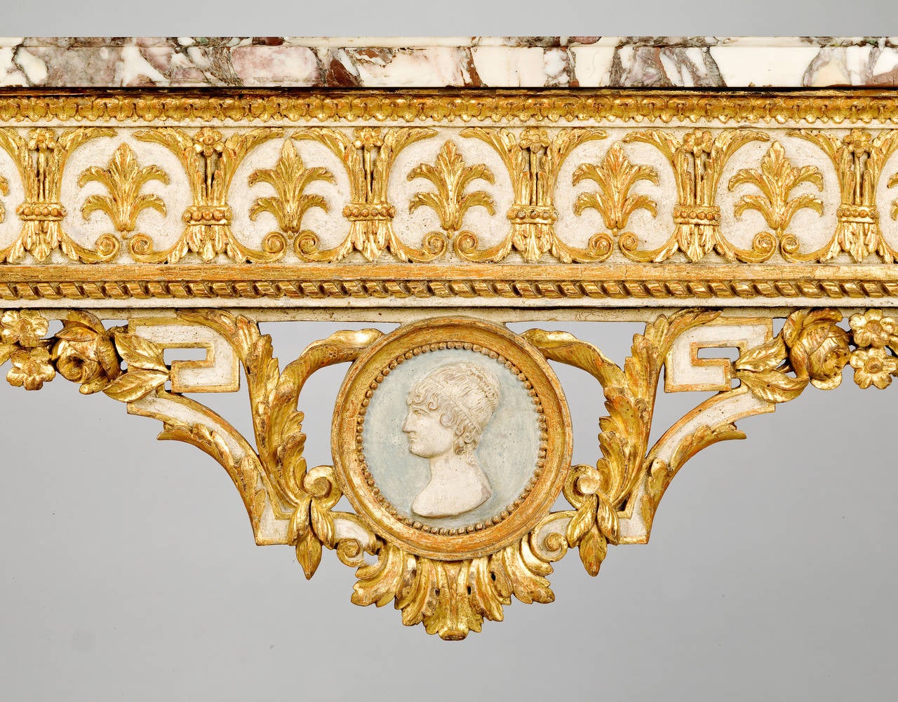 An unusual, fine quality late 18th century Piedmontese parcel-gilt side table. The frieze is decorated with enclosed anthemia and at the centre there is suspended a carved profile portrait of a young lady supported by a key pattern surrounded by