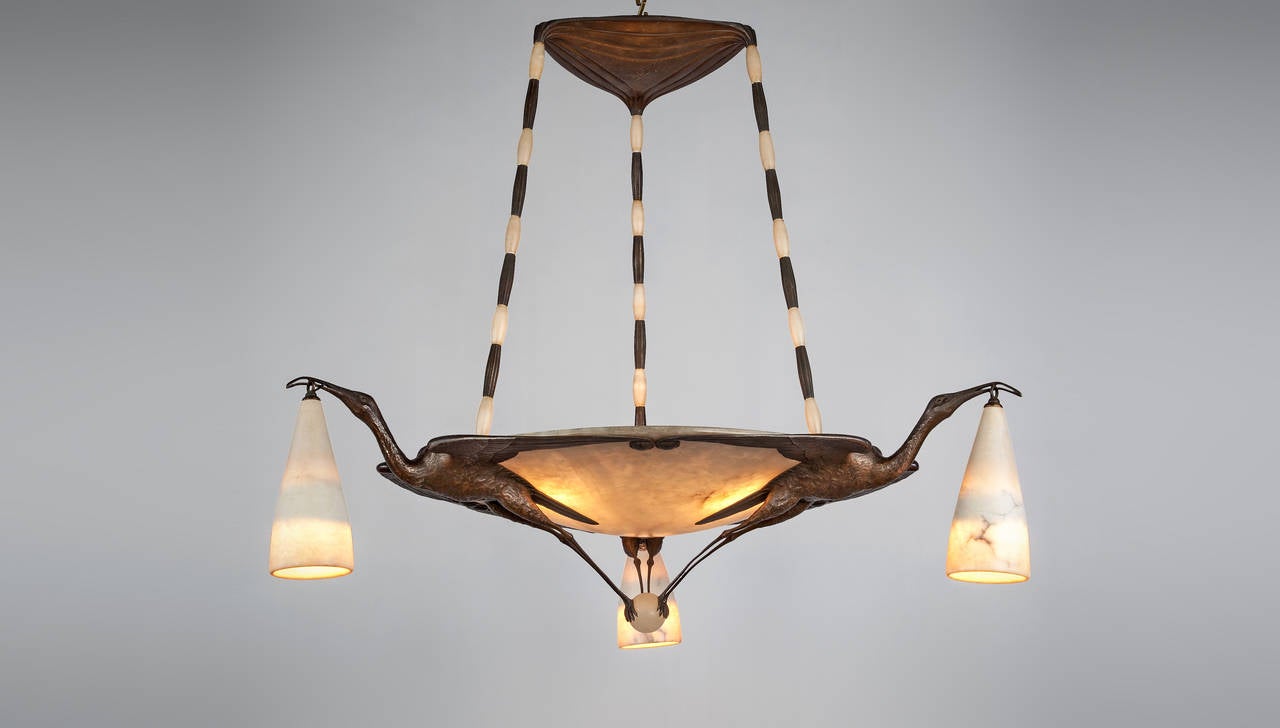 A silvered and patinated bronze chandelier with alabaster dish and shades. Signed 'Albert Cheuret' on the central ceiling rose. 

Albert Cheuret was a French bronze sculptor born in 1884 and a talented figure of the Art Deco movement in Paris.