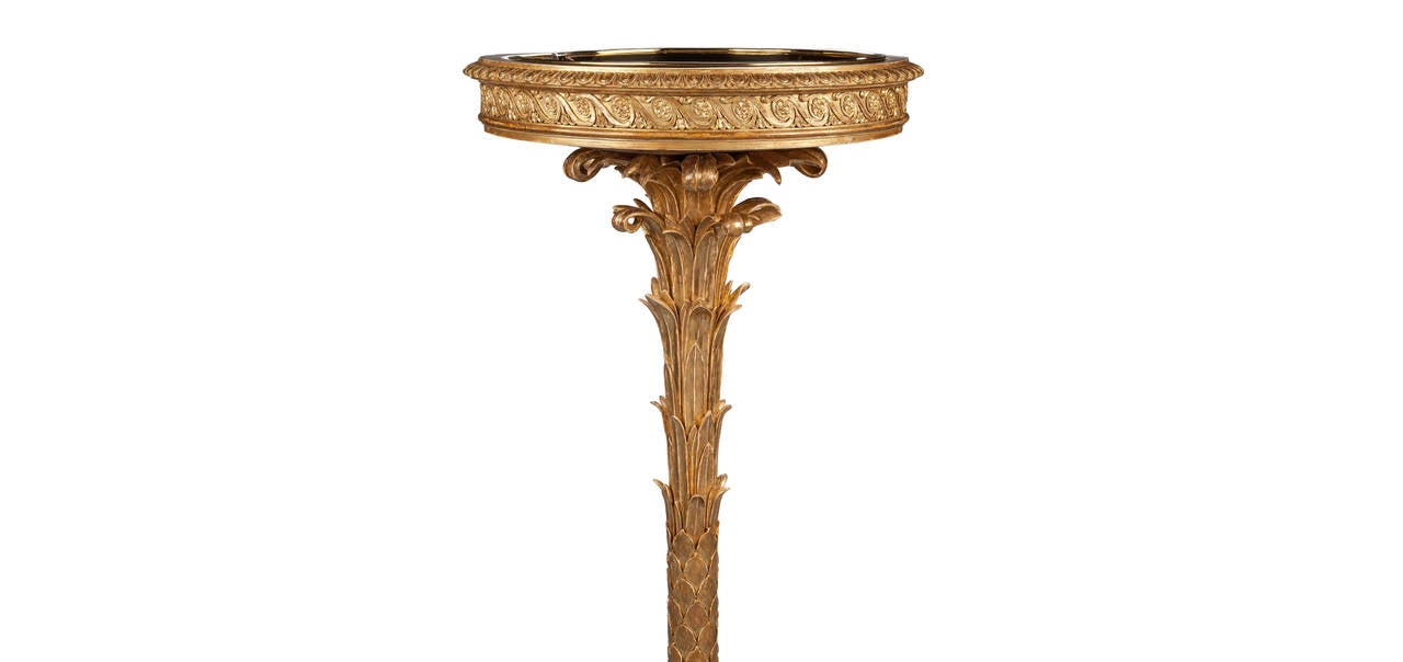 A rare and unique pair of early 19th century giltwood jardinieres, the circular tops with inset brass liners, the egg and dart beveled edge above a band of floral vitruvian scrolling, supported on a stylised palm tree column, the circular base with