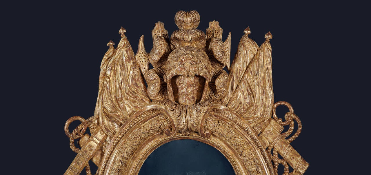 A unique late 17th century William III carved giltwood looking glass. The oval central plate with an inner border of harebell husks, a central border of oak leaves and scallop shells and an outer border of mermaid scales. The cartouche with a