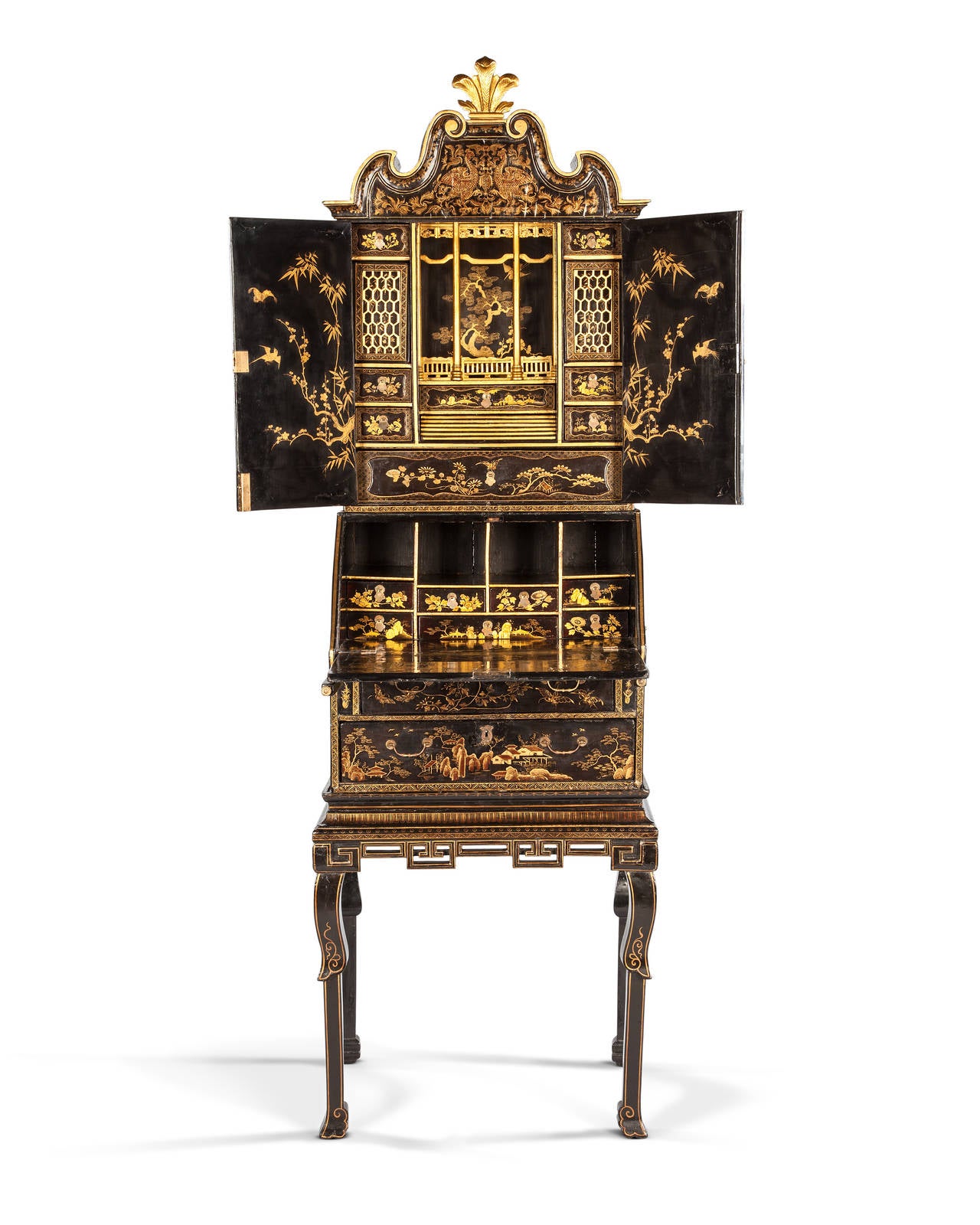 An early 19th century Chinese export miniature table cabinet on stand. The shaped corners centred with Prince of Wales feathers above two panelled doors, opening to reveal a stylised temple interior with pierced screen drawers, and a series of small