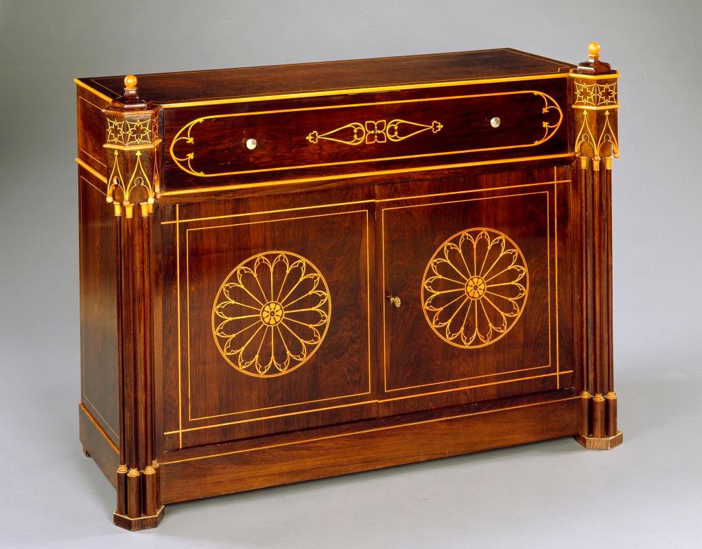 A Charles X rosewood secretaire commode. The front corners are fashioned as gothic cluster columns with boxwood marquetry gothic arches and inlaid paterae. The front upper frieze is inlaid with a gothic oval and opens to reveal a desk drawer lined