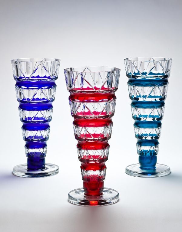 Three 10 sided cut glass vases of flared conical form with bands of cobalt blue, red and aquamarine casing each standing on a stepped foot. Designed by Charles Graffart, all with an impressed mark.

Location: NY