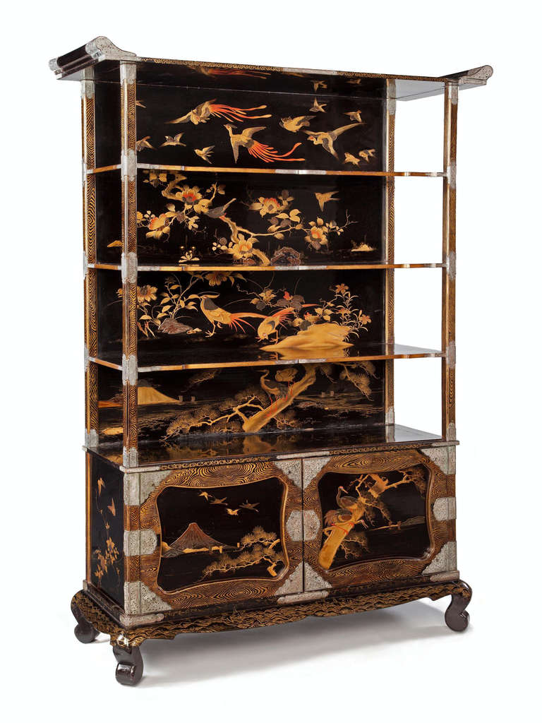 A highly unusual Japanese Meiji period lacquer cabinet etagere decorated with an ascending avian landscape in low relief, with Mount Fuji in the background and flying cranes and phoenix on the upper tier. The doors and supporting elements decorated