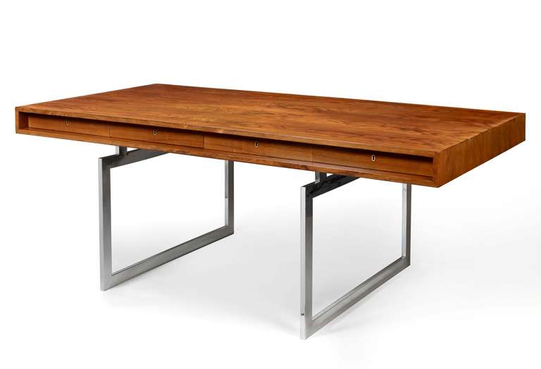 A fine and early steel and rosewood modernist desk, designed by Danish architect Bodil Kjaer,(1932), the body of the desk with four recessed lockable drawers, supported on chromed steel legs. Retaining its original free-standing cabinet with a deep