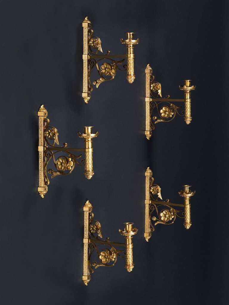 An exceptional set of ten aesthetic movement gilt bronze wall lights. The candle arm is decorated with an overlapping leaf motif, supported by stylized scrolls. The back plate is a half hexagon enriched with an incised diaper pattern.<br />
England,