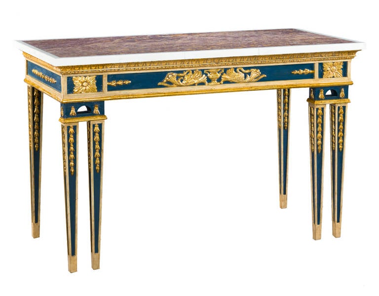 A pair of cream and blue painted, parcel gilt side tables with pink mottled marble tops within white borders; above egg and dart friezes, the aprons centred by urns and stylised swan cornucopia, the square tapered panelled legs with carved