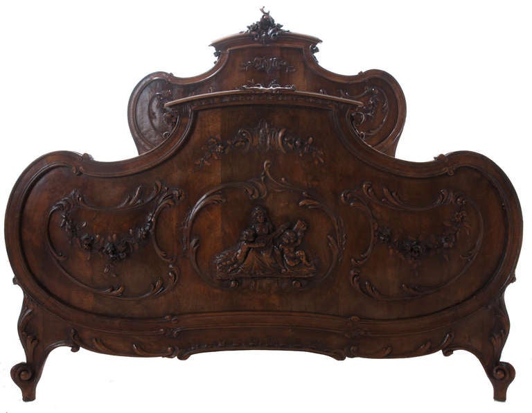 The Bed:
The headboard: The carved shaped crest centered with a “C” scroll floral and foliate motif over a highly carved back panel centered by an elaborately carved basket, floral and foliate motifs flanked by floral swags encircled by carved