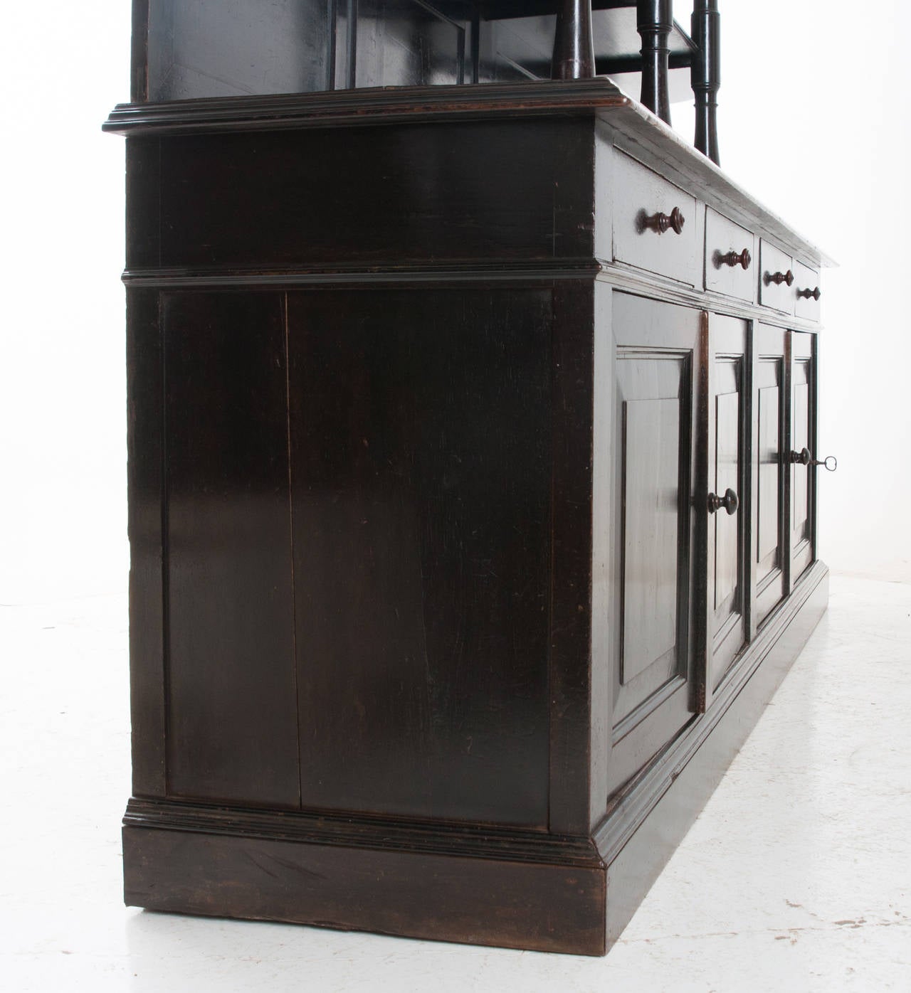 A breathtaking Art Deco 1920s bar back from a restaurant or bistro in painted black mahogany. The three turned mahogany center styles make this fine bar outstanding. We love the paneled back of the shelves with the scalloped sides. The enfilade base