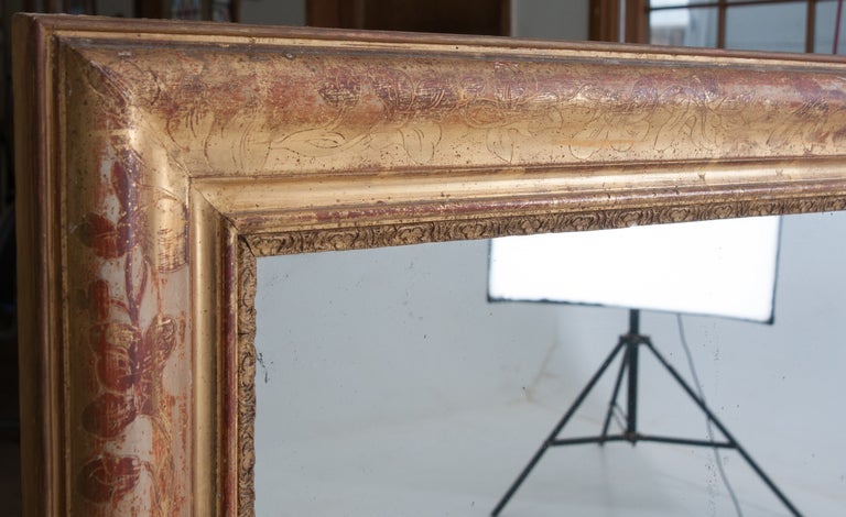 French over mantle mirror with ivy motif and original mercury glass. Gold gilt wood mirrors are made of wood, then rubbed with a white plaster - like material, next they were painted with a rouge paint which the gold gilt adheres to. Over the many