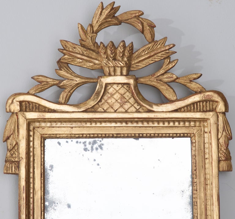 French Louis XVI style gilt-wood mirror with pierced crest depicting a wreath around arrow heads and feathers from the 1780's with original mercury mirror glass.