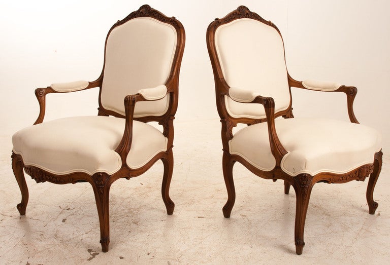 French Louis XV style carved dark walnut chairs. Carvings of seashells, flowers and swirls. Great size chairs with curved back, the whole resting on escargot feet. White upholstery is more recent with the classic French check used on the back of