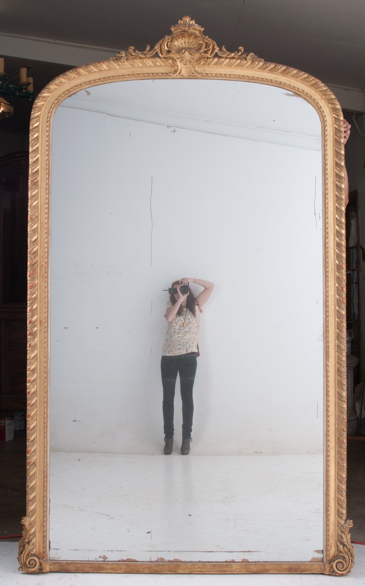 A massive mantle mirror in the Louis XV style, carved and gold gilt. Original mirror glass does have some foxing and crystallizing. Be sure to see the detailed photos, there are areas especially along the bottom where the mirror is missing. You can