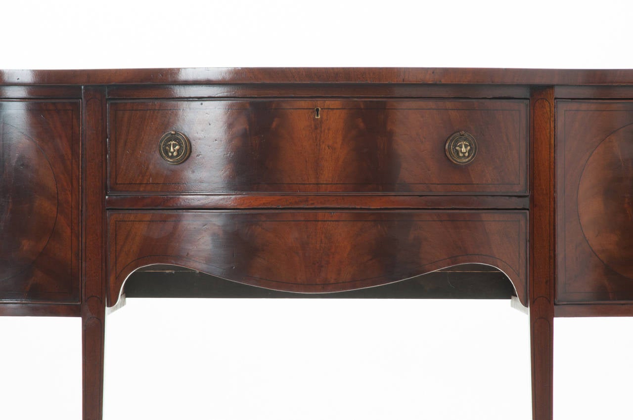 A wonderful dramatic serpentine front mahogany sideboard. Starting from the left is a concave door front opening to a large storage space, the middle is two stacked convex drawers with dividers in the bottom drawer and lovely scalloped apron. To the