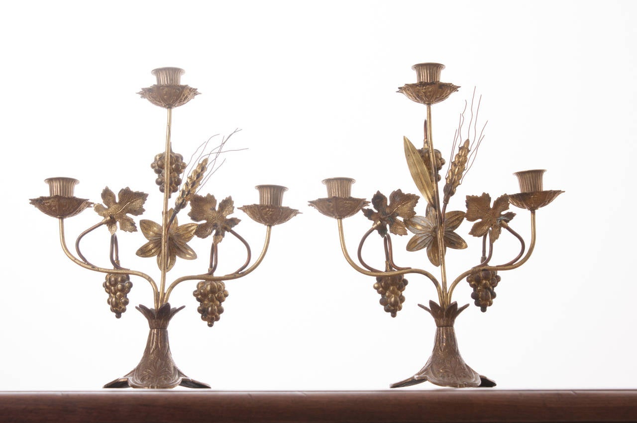 French Pair of 20th Century Brass Candelabra from A Church Altar

A darling pair of candelabra from a church altar with three candle cups each. The candlesticks are decorated with grapes, wheat, leaves and flowers all over a decorative triangular