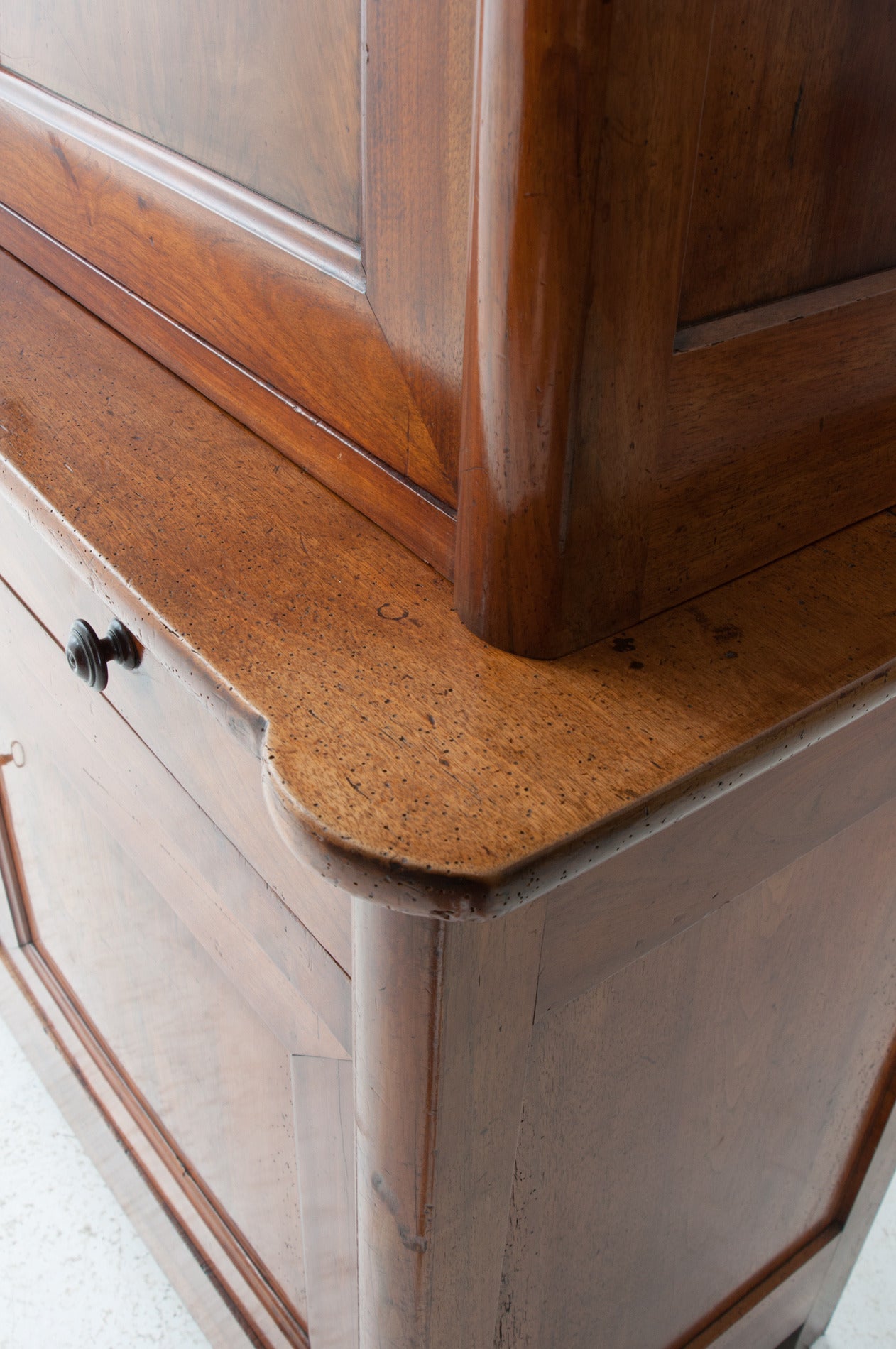 A handsome walnut buffet a deux corps in the Restoration fashion. The pronounced rounded corners of the flat top cornice are impressive, and continue rounding down the front corners of this fine buffet, the perfect storage piece! Two large doors on