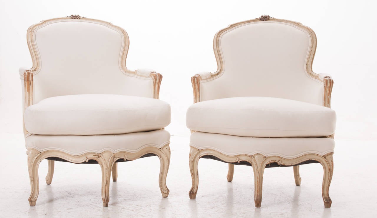 French pair of middle 1800s Louis XV bergeres 

The shaped padded back surmounted by moulded crest with floral and foliate motifs, joined to outscrolled padded arms, with cushion seat, raised on five cabriole legs, three in front, two in