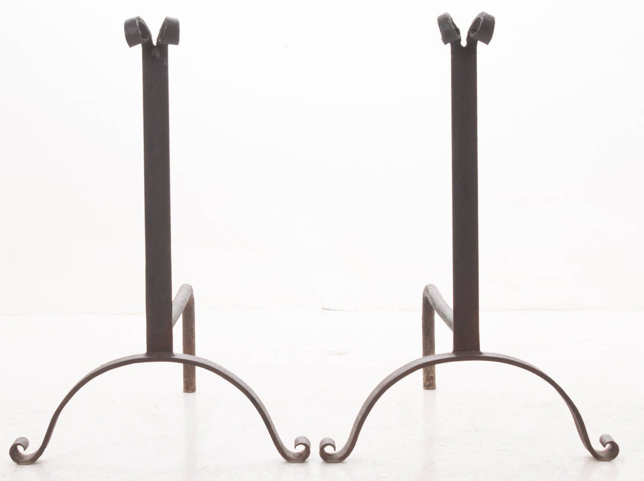 A large pair of hand forged iron andirons in a simple design, made in the early 1800s