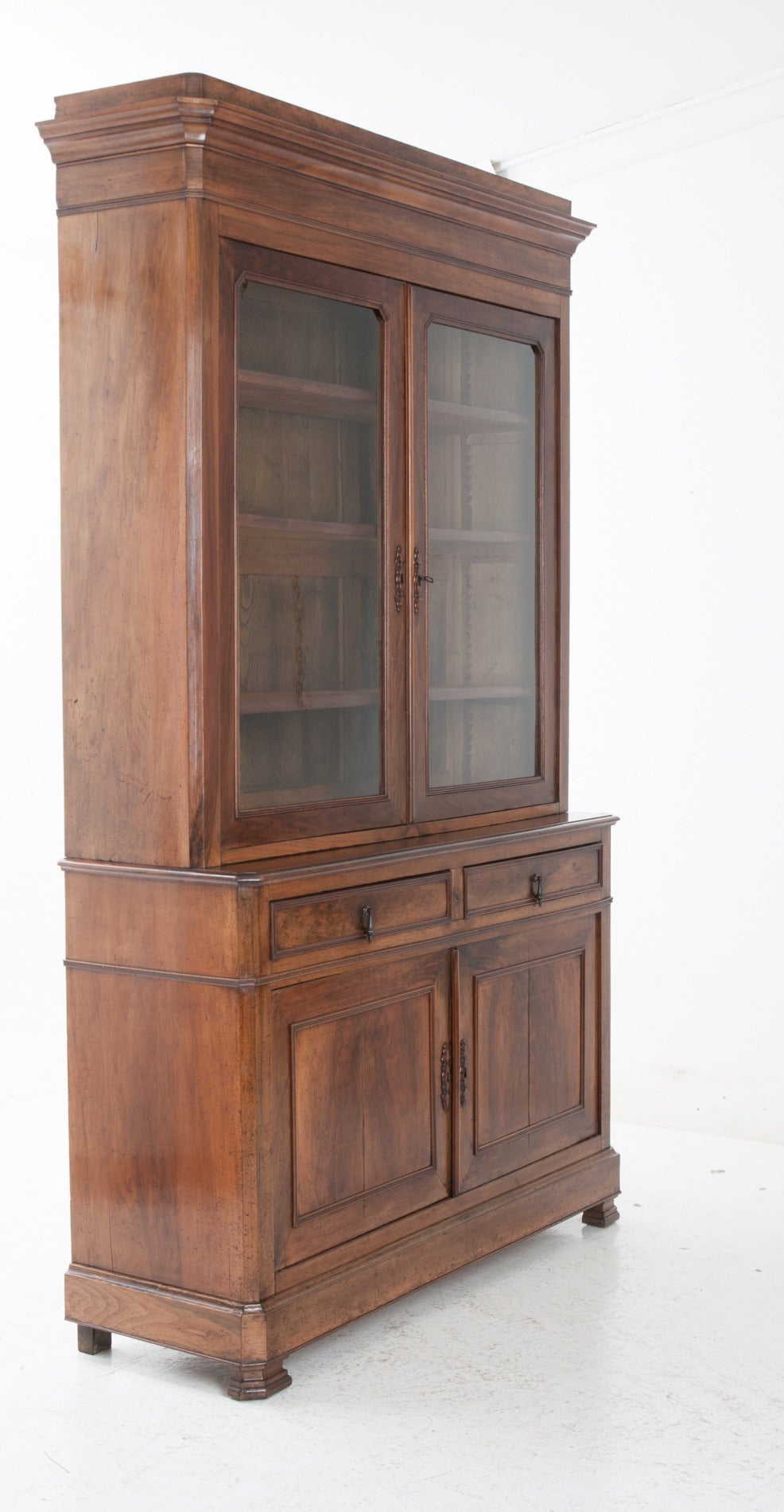A handsome Louis Philippe mahogany buffet a deux corps with original, oversized, old wavy glass panes in the top, the interior has three adjustable, original finished shelves. This simply carved and designed buffet allows you to enjoy the fine wood