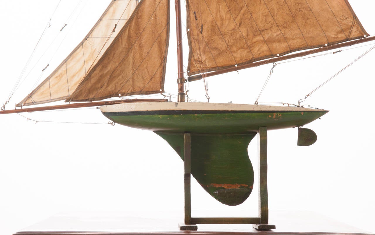 A Classic handmade mini pond boat from the 1920s. This yacht has a quality lacquer finish, all original wood hull, cotton sails and wood stand.