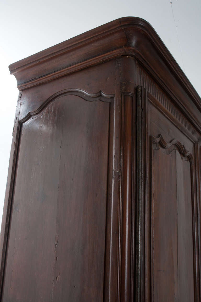 A gorgeous carved walnut armoire of transitional Louis XV taste. Wonderful rich, original color and patina. Steel barrel hinges hold the two large doors, with original escutcheon plates and working locks, opening to a blue painted interior with