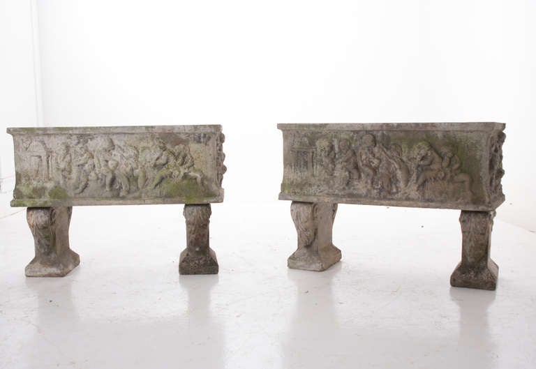 A stunning pair of thick, decorative stone planters featuring children playing instruments in the garden and riding a lion's back. Wonderful patina, made of reconstituted stone around 1900.