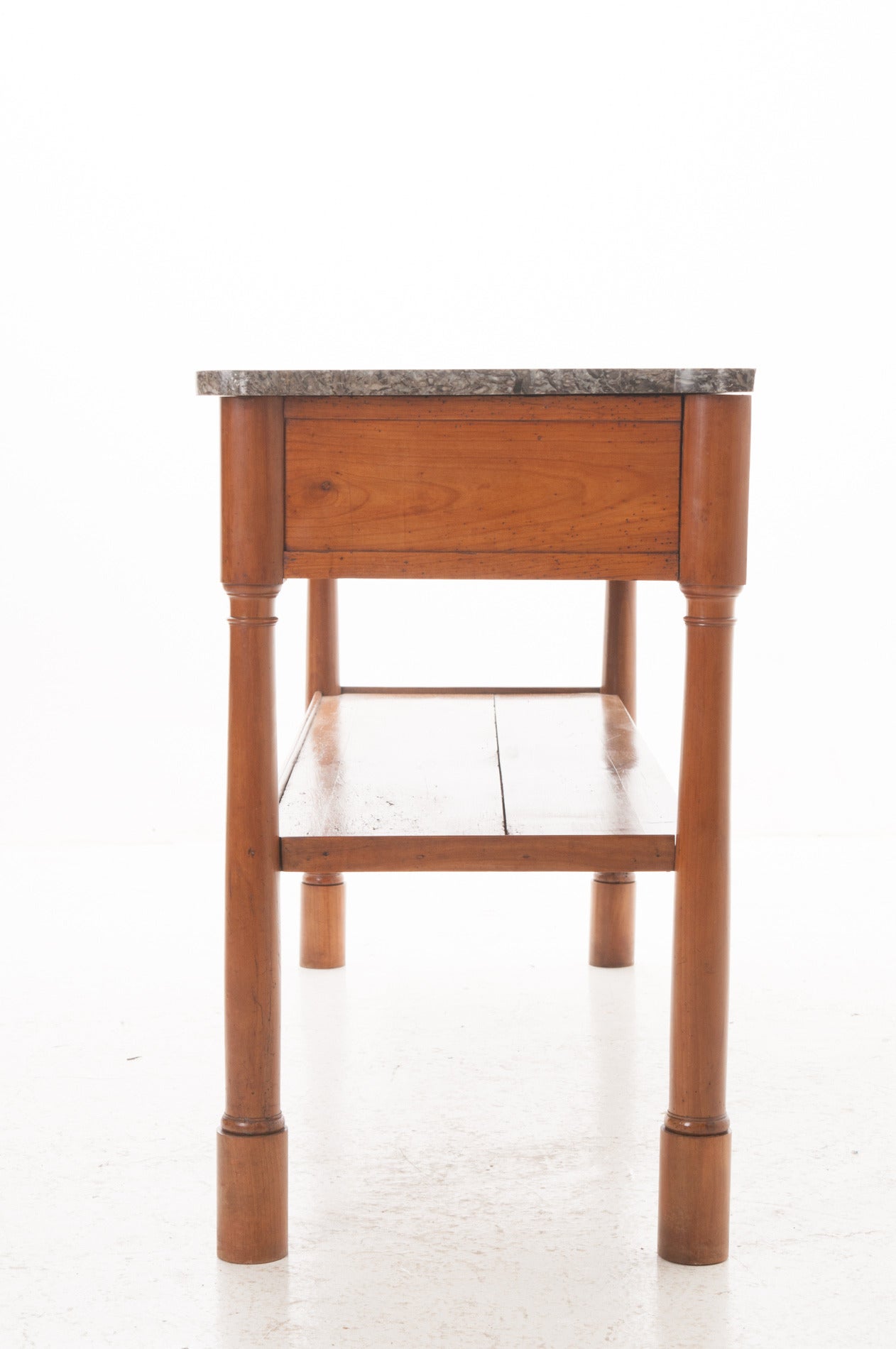 A gorgeous cherrywood server with its original shaped marble top. Three dovetailed, working drawers grace the front side of the simple apron. Interesting turned wood legs tapered down, all connecting with a simple stretcher shelf. 1810 The original