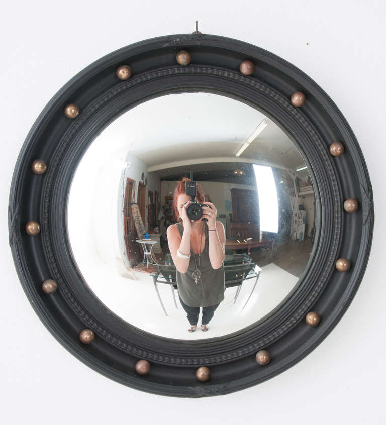 Convex mirror with carved ebonized frame featuring round brass balls, black ebonized reeded frame holds in the mirror glass.