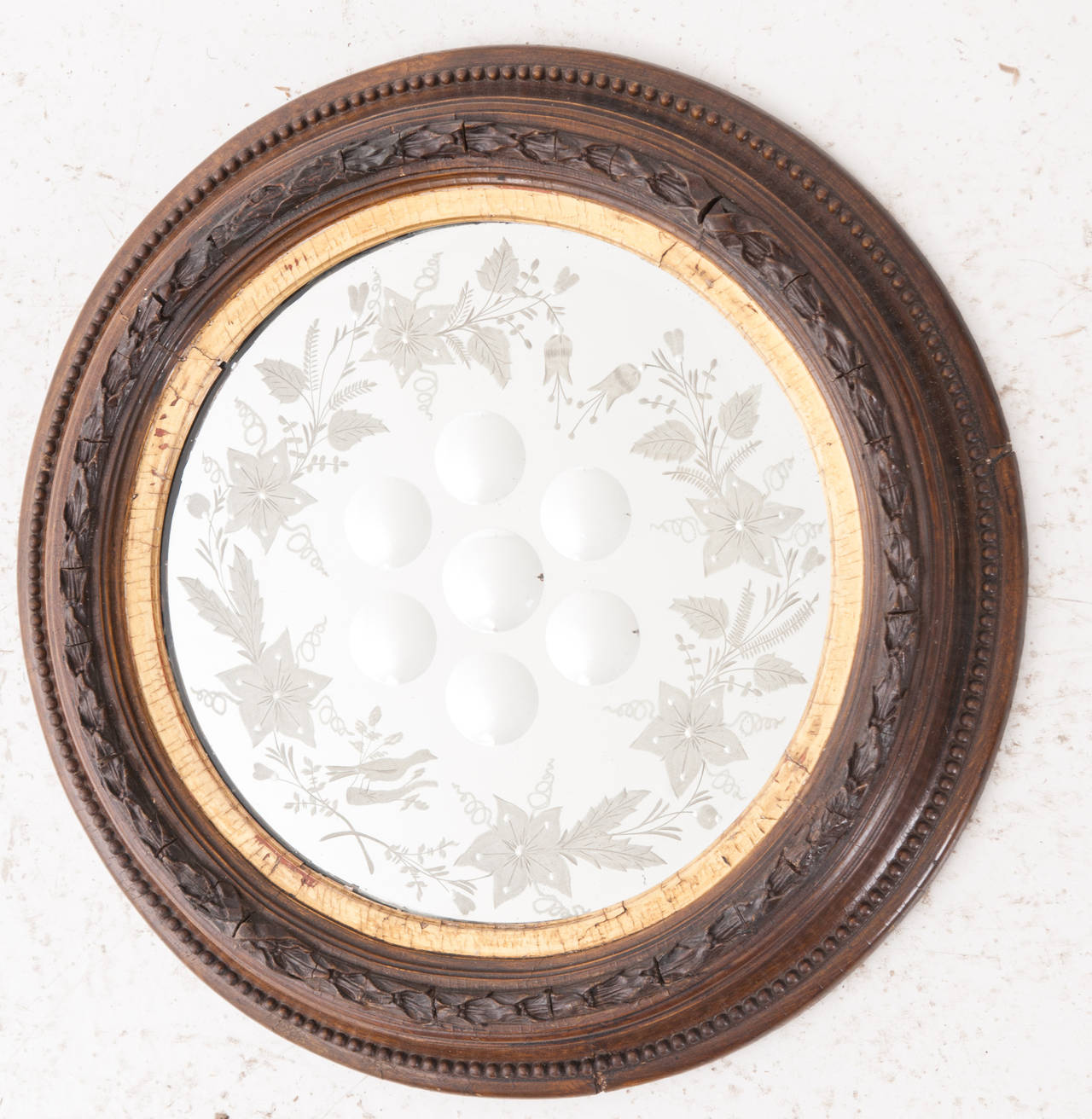 A fabulous circular bull's eye mirror with seven convex mirrors surrounded by detailed etching of flowers and greenery! Gold gilt banding surrounds the original mirror with a hand carved wood frame. 1860's