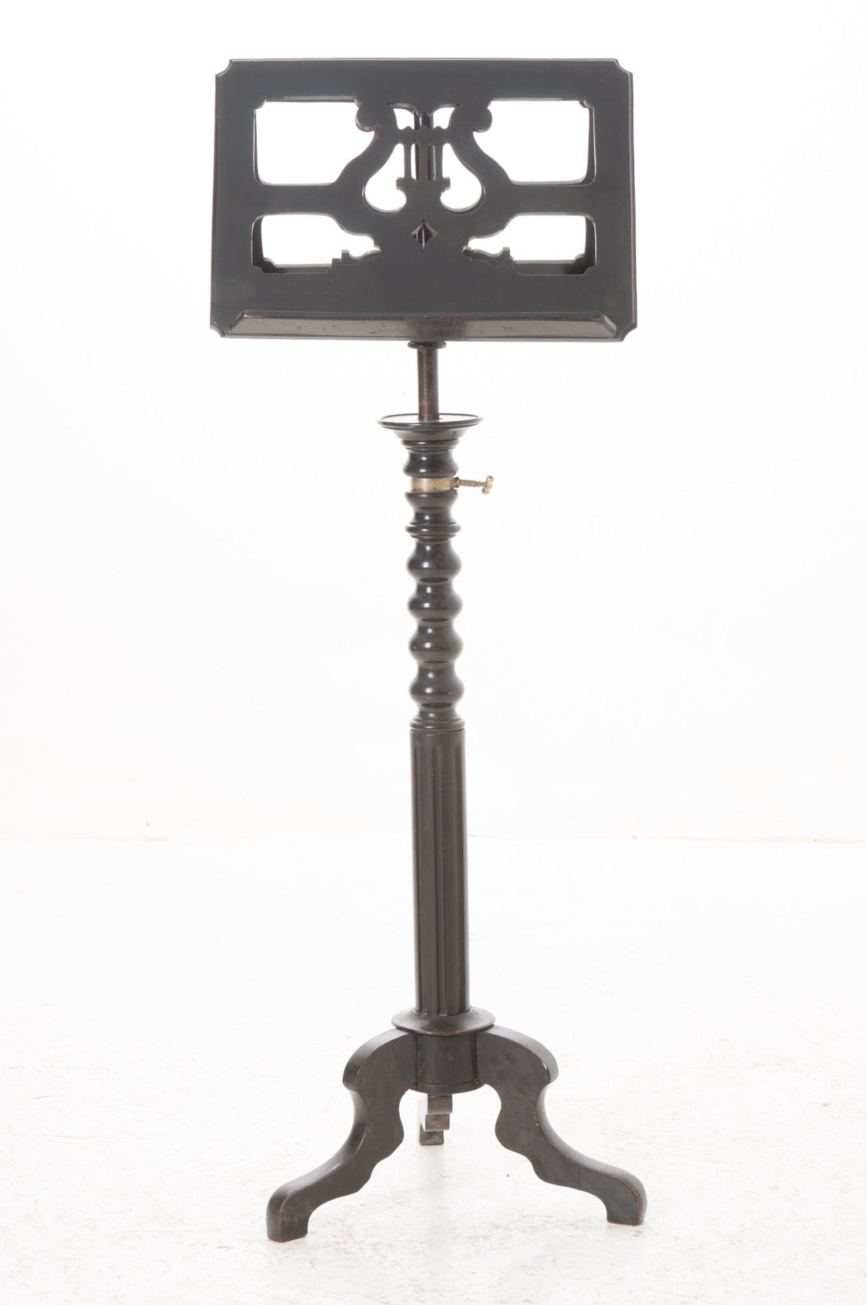 A darling duet sheet music stand having lyre decorations with sturdy resting surfaces on each side for sheet music or books. The stand can be adjusted for height using the original brass hardware over a turned wood and fluted column ending in a