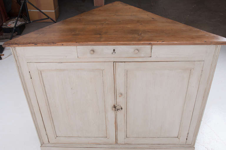 Large size corner cabinet buffet made of pine. The top of the cabinet has a wonderful worn pine patina, the base of the cabinet has its original paint finish. One single locking drawer sits above two large doors opening to two shelves. Corner