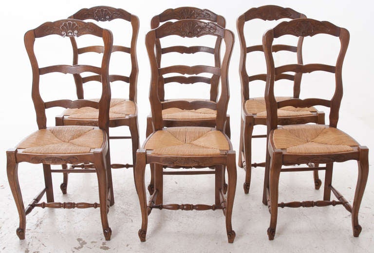 French 1940's oak ladder back chairs with carved shells with rush seat, they are in great condition. Price is for the set of 6. Seat height is 17 3/4