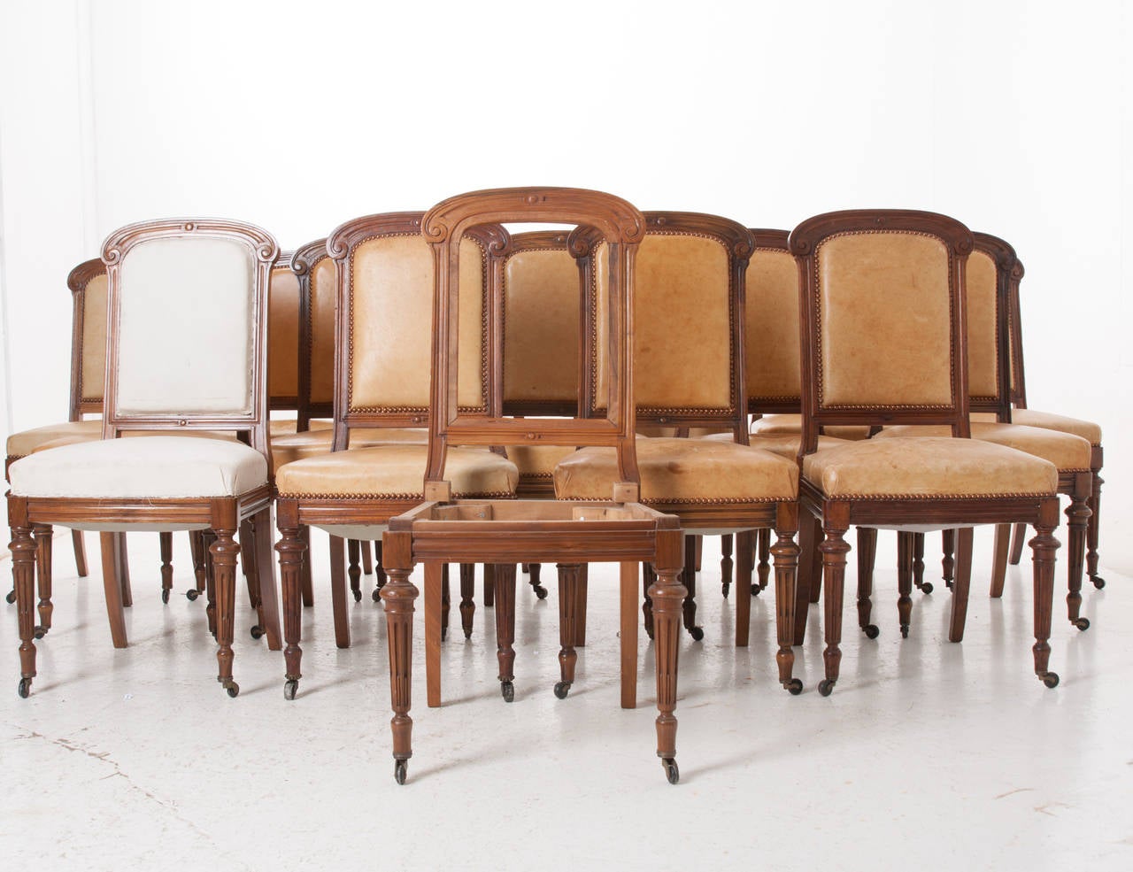 An amazing set of 16 carved walnut dining chairs all in excellent condition! Each chair has casters on the front two legs, an old dining chair tradition, for easily pulling a lady's chair out. The set has old upholstery and would need to be