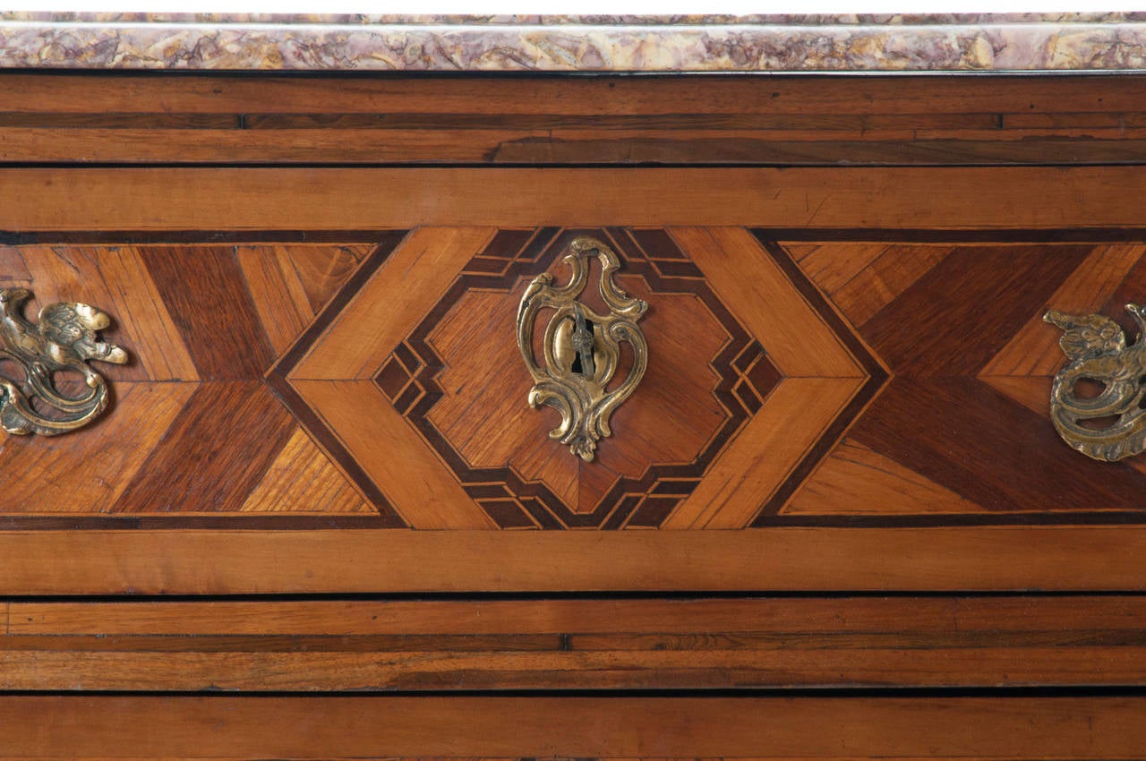 French Louis XV serpentine inlay of mixed woods commode with original shaped multicolored marble top. Two fine dovetailed drawers have stunning geometric inlay designs. Brass drawer pulls, escutcheon plates and leg caps are impressive. See detailed