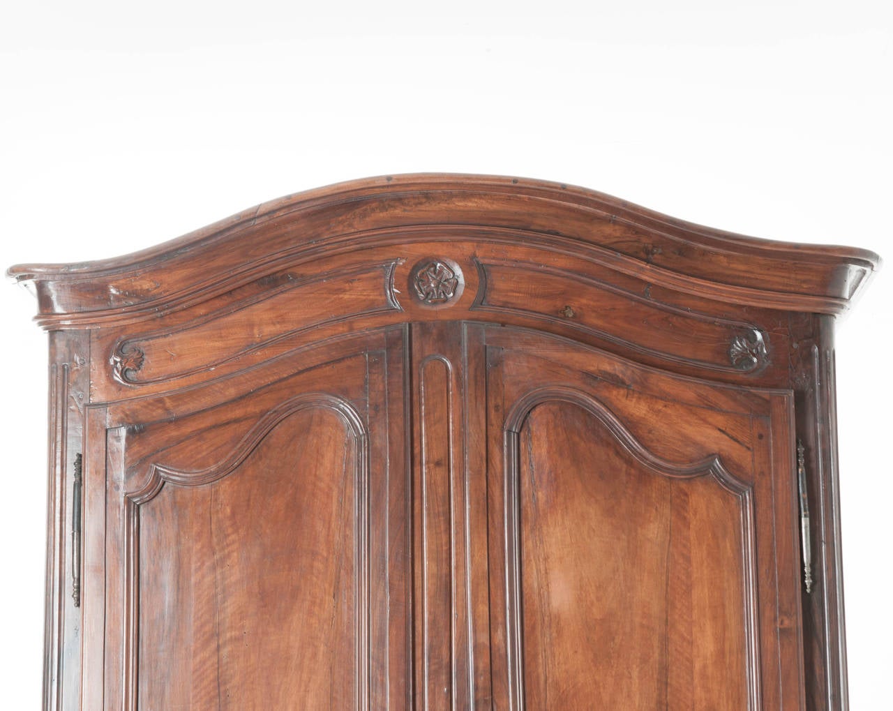 A grand 18th Century carved solid walnut armoire with the iconic, Chapeau De Gendarme crown over two tall paneled doors. All original steel barrel hinges and hardware. It opens to three shelves and two drawers for lots of storage. This armoire