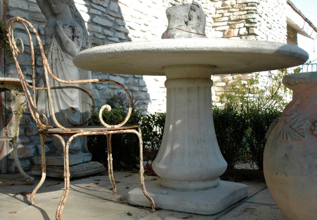 Reconstituted stone garden tables with a pedestal base and thick table top. They are separate pieces. There is a hole for an umbrella(the head sitting on the table is a different item)