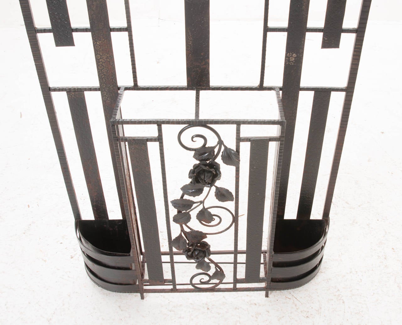 A fabulous iron hall tree made in the Art Deco period with: original beveled mirror glass with light under decorative glass, marble shelf, 4 hooks and two umbrella / cane stands! The texture on the metal and metal rose vines compliment this piece