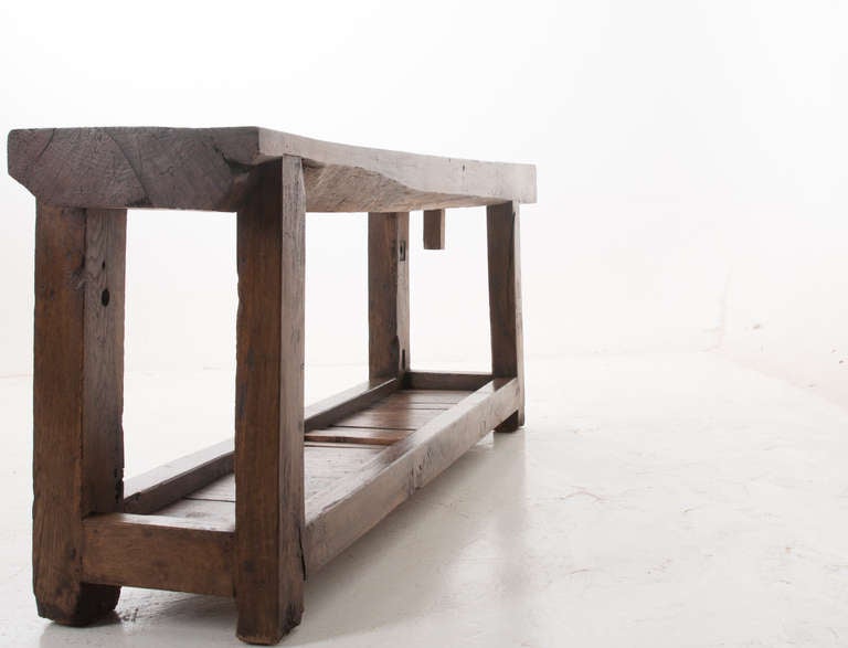 Industrial workbench from Burgundy, France with a very thick cut top, 1860s. Wear and patina is found throughout this fine table with cut outs, imprints and saw marks, great stretcher shelf below. 