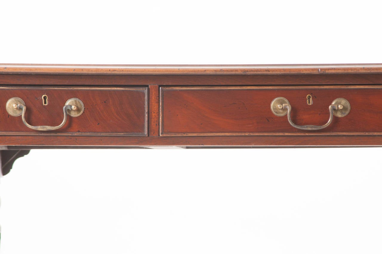 A handsome English mahogany desk with inset leather writing surface. This desk is very functional, and finished all the way around with six locking drawers, three on each side. All original brass drawer pulls and escutcheons. Impressive carved desk