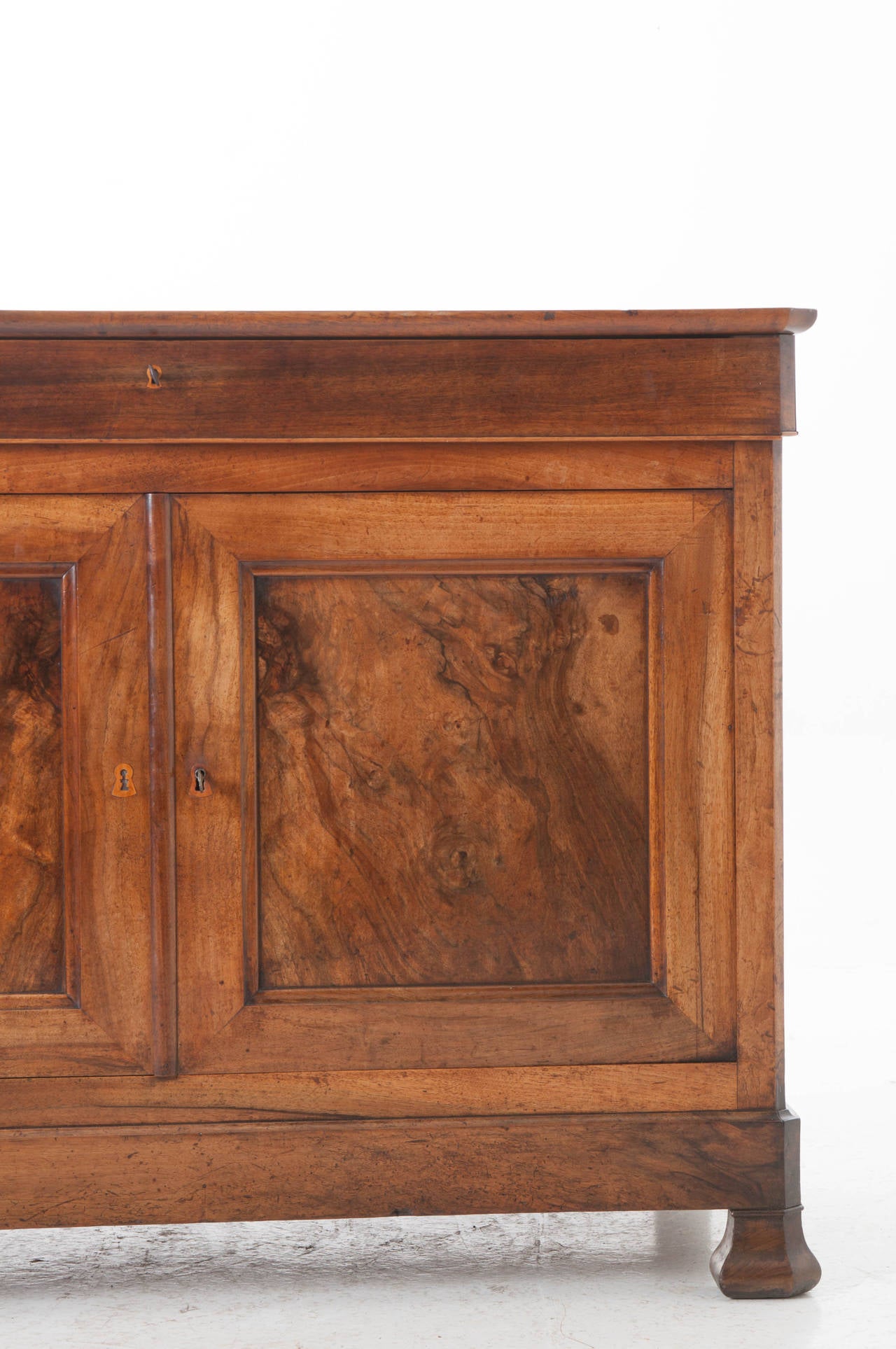 A gorgeous Louis Philippe buffet with a single drawer and two burl walnut doors. The simple lines of this antique allow you to enjoy the wood and patina to the fullest! A breathtaking buffet that would look faboulus in any interior! See the detailed