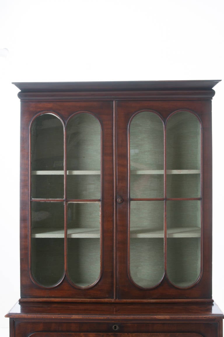Elegant English secretary made of burled mahogany with bookcase top featuring old wavy glass, the interior has a blue colored fabric and wrapped fabric adjustable shelves, making for a wonderful contrast to the mahogany of the secretary. Below is a