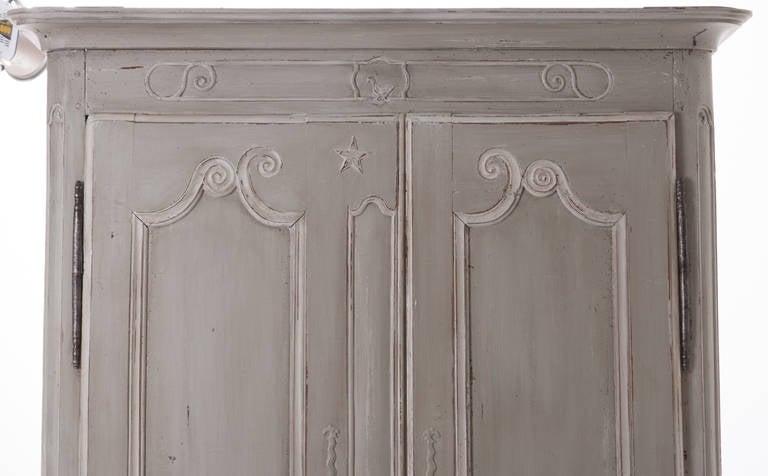 A darling hand-carved and hand pegged fruitwood armoire with new fresh exterior paint finish. This is a fine armoire from the 1700s with its own Primitive asymmetrical carvings. You can really see the age on the back boards and entire interior as