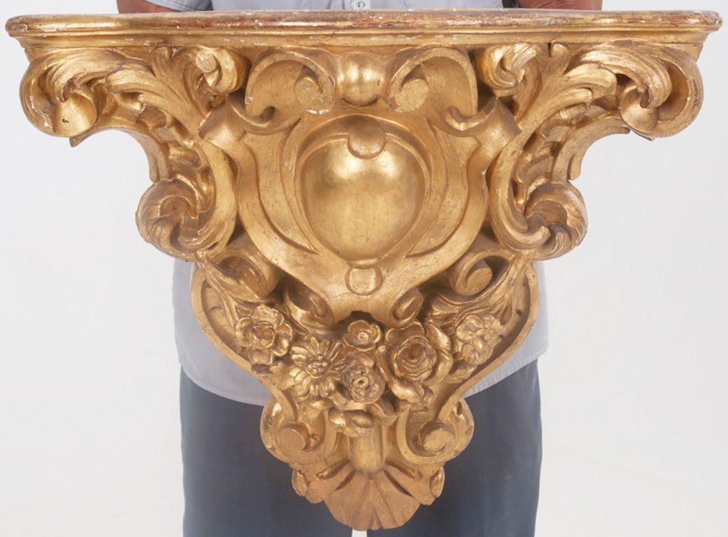 Louis XV Style and Rococo influenced gilt wood corner console. Carved wood decorated with scroll work, leaves and flowers. c.1890.
