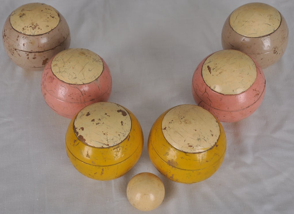 European boccee ball set with 6 carved and painted wood balls with 2 balls of the same color (2 pink, 2 yellow and 2 gray). This particular set is ment to play with 3 players with a smaller target ball made of ivory.