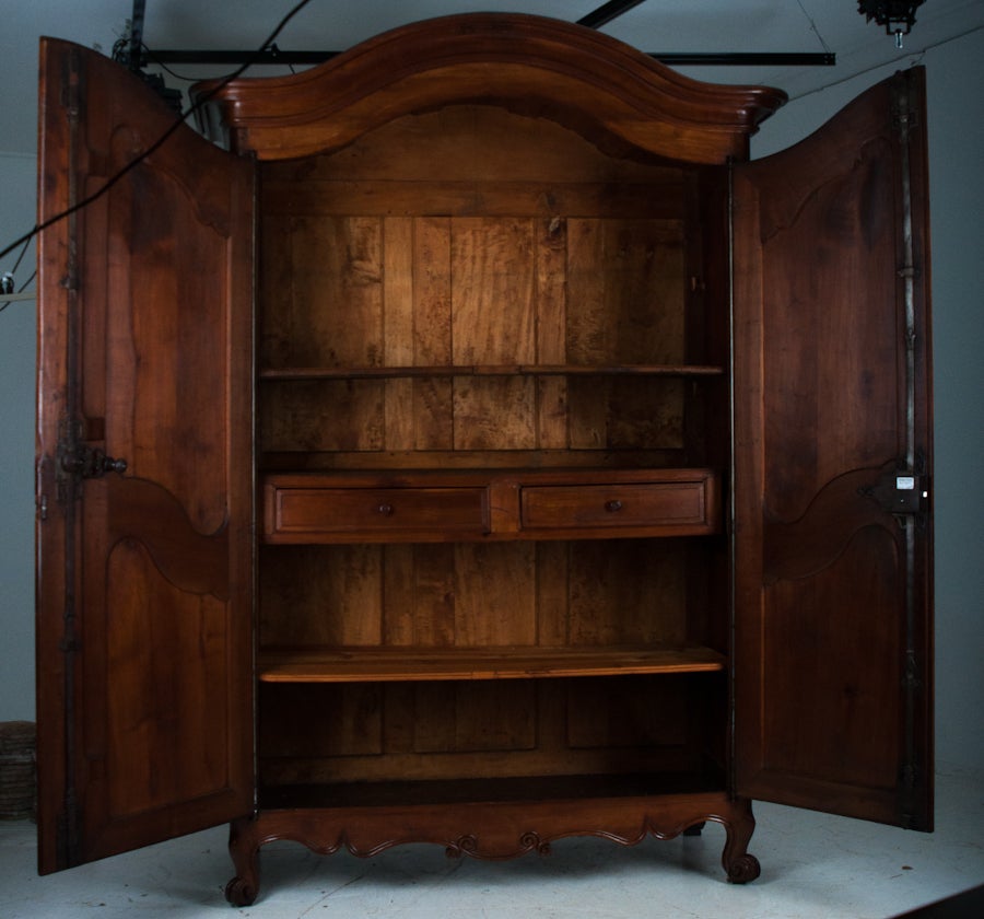 Louis XV style armoire from the south of France , early 1800's, very old cherry wood as you can see the excellent patina. The armoire has a shaped Chateau de Gendarme crown over a large body flanked with handsome full barrel hinges which feature a