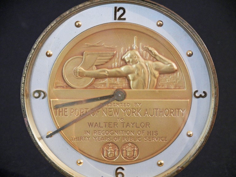 A magnificent combination of figural sculpture and streamlined, late Art Deco design, this wind-up clock -- presented to an employee of the Port of New York Authority for thirty years of public service -- is dominated by a large, 3 inch gold