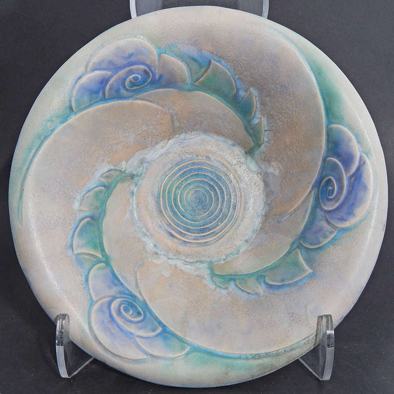 Un classico esempio di design Art Déco, con il suo vortice impreziosito da fiori stilizzati, questa rara ciotola è stata prodotta dalla ceramica Denby Pottery England.  Gli smalti sono deliziosi: un grigio violaceo che contrasta con un verde tenue e