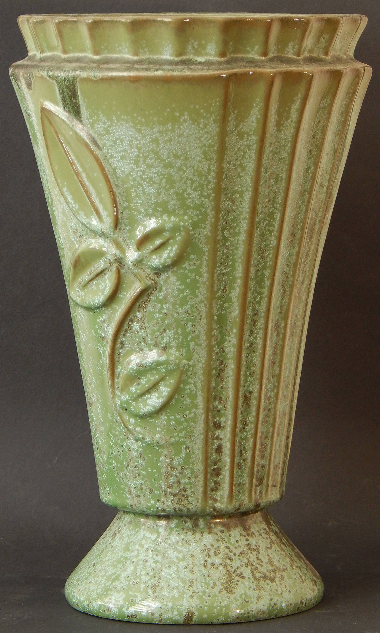 A very rare form, but glazed with the gorgeous mottled and streaky glaze that Fulper Pottery was famous for, this fluted, flaring vase is decorated with deep bas relief leaf and branch forms that are stylized in the Classic Art Deco manner. Founded