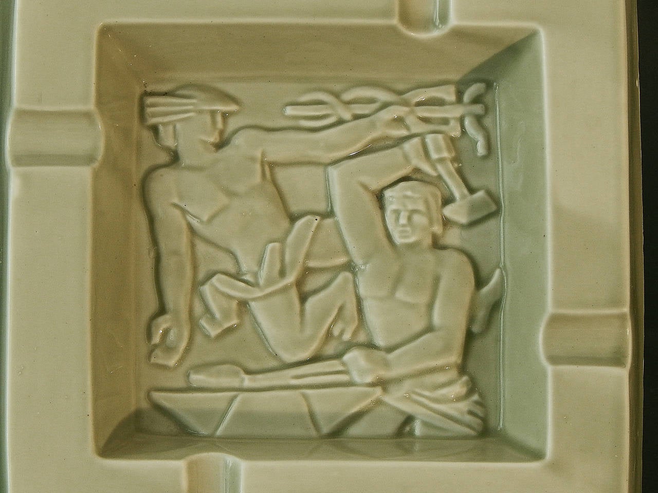 Rare and striking, this Art Deco ceramic dish/ashtray depicts, in bas relief, stylized figures of Mercury and Vulcan, constituting the logo of the Fernand-Belliard forge in Bordeaux, France. The logo, also used on the firm's letterhead and other