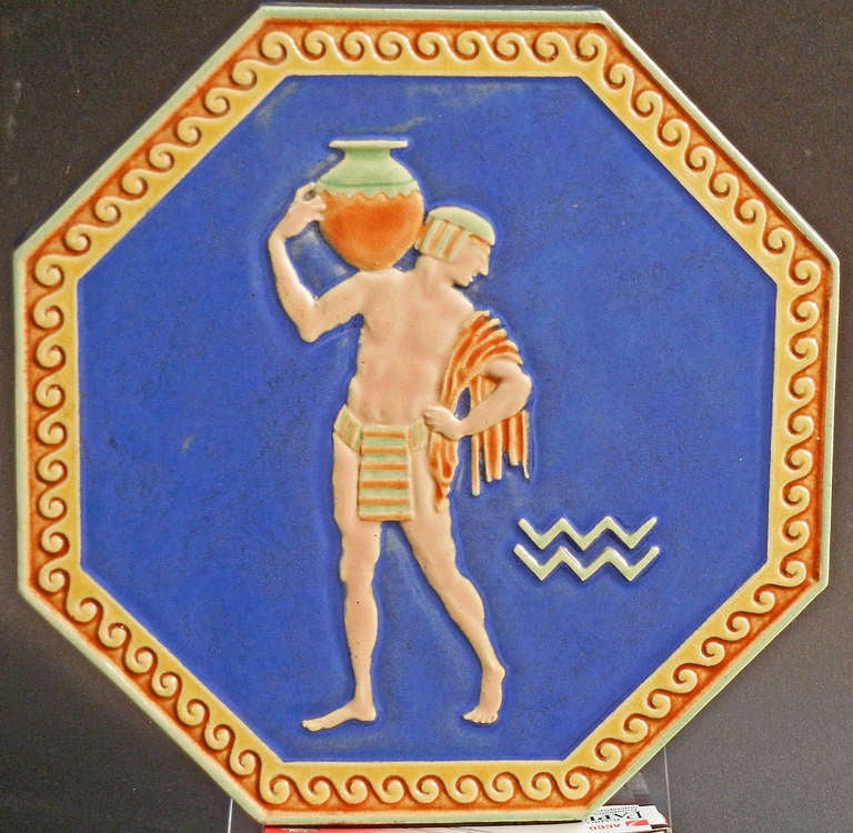 Beautifully sculpted and glazed in tones of indigo, straw and burnt orange, this very fine and rare octagonal tile was made in Italy. Depicting a nude male water carrier in Egyptian dress, this piece gives evidence of the Western world's infatuation